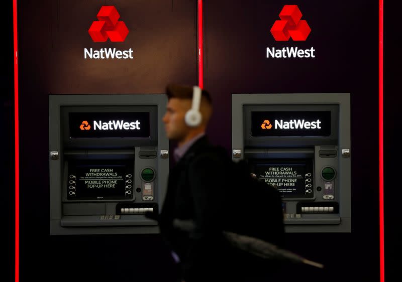 FILE PHOTO: A man walks past ATM machines at branch of the NatWest bank in Manchester