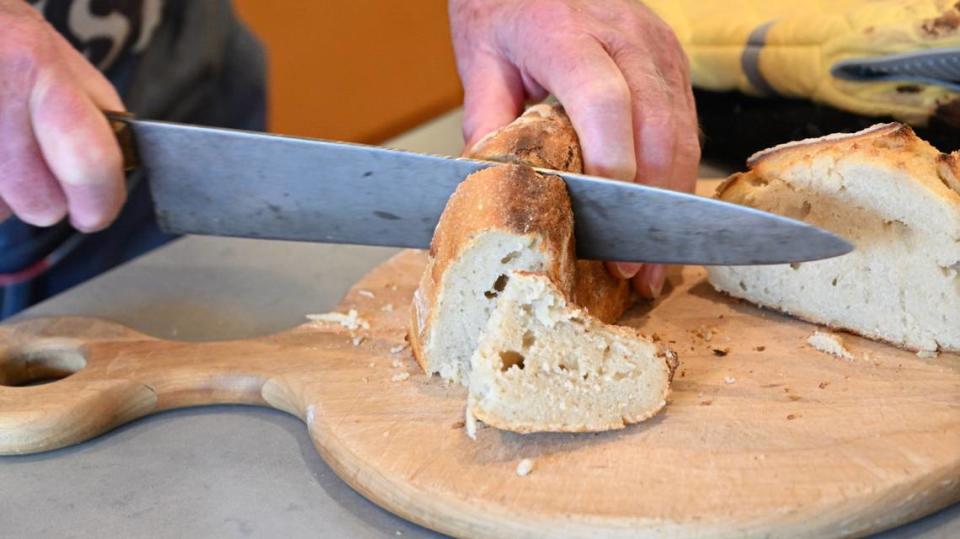 Melvin “Gabe” Gabelhaus, 98, slices fresh sourdough bread at his home in Modesto, Calif., Tuesday, August 22, 2023. Gabelhaus bakes several times a week and gives most of the baked goods to friends and neighbors. Andy Alfaro/aalfaro@modbee.com