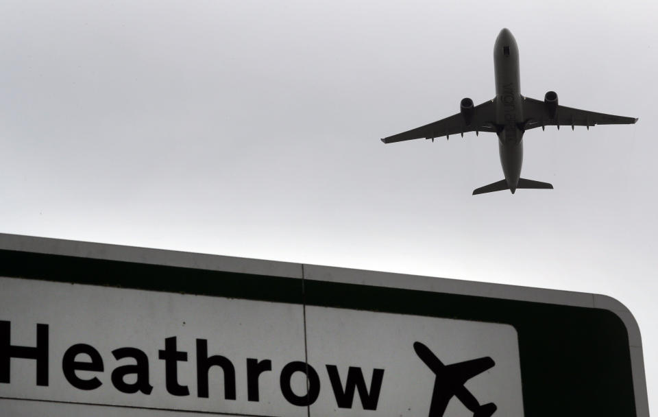 FILE - A plane takes off over a road sign near Heathrow Airport in London, June 5, 2018. The British government says it will grant extensions to several large U.K. airports unable to meet the June 1, 2024 deadline to fully install new scanning technology that would have allowed passengers to take two liters (70 ounces) of liquid in their hand luggage — rather than the current paltry 100 milliliters (3.5 ounces). (AP Photo/Kirsty Wigglesworth, file)