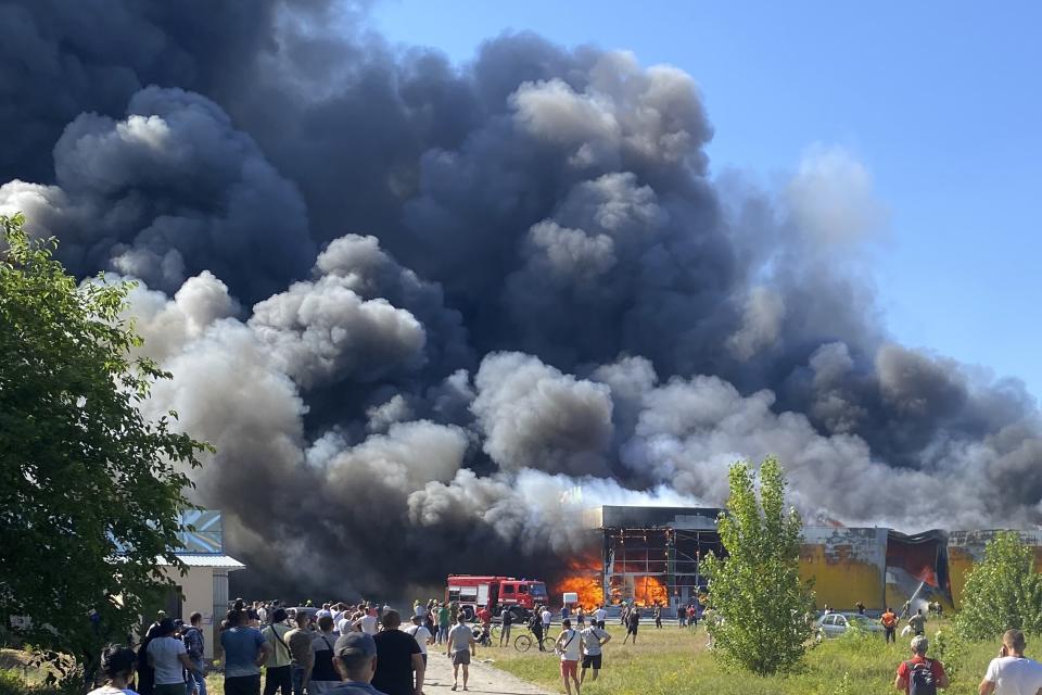 FILE - People watch as smoke bellows after a Russian missile strike hit a crowded shopping mall, in Kremenchuk, Ukraine, Monday, June 27, 2022. It has not been an easy week for Russian President Vladimir Putin. He took his first foreign trip since the invasion of Ukraine to shore up relations with troublesome Central Asian allies. And he was forced to deny that his troops had yet again attacked a civilian target in Ukraine. (Viacheslav Priadko via AP, File)