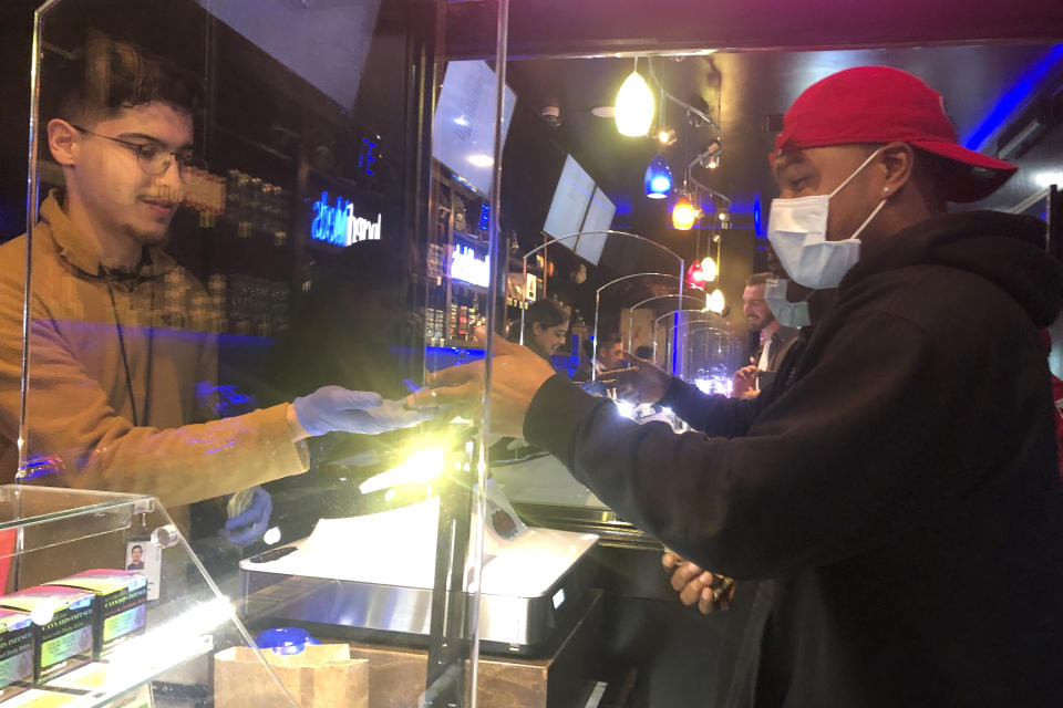 A customer who wished to remain unidentified, right, wears a mask while shopping at The Green Cross cannabis dispensary in San Francisco, Wednesday, March 18, 2020. As about 7 million people in the San Francisco Bay Area are under shelter-in-place orders, only allowed to leave their homes for crucial needs in an attempt to slow the virus spread, marijuana stores remain open and are being considered "essential services." (AP Photo/Haven Daley)