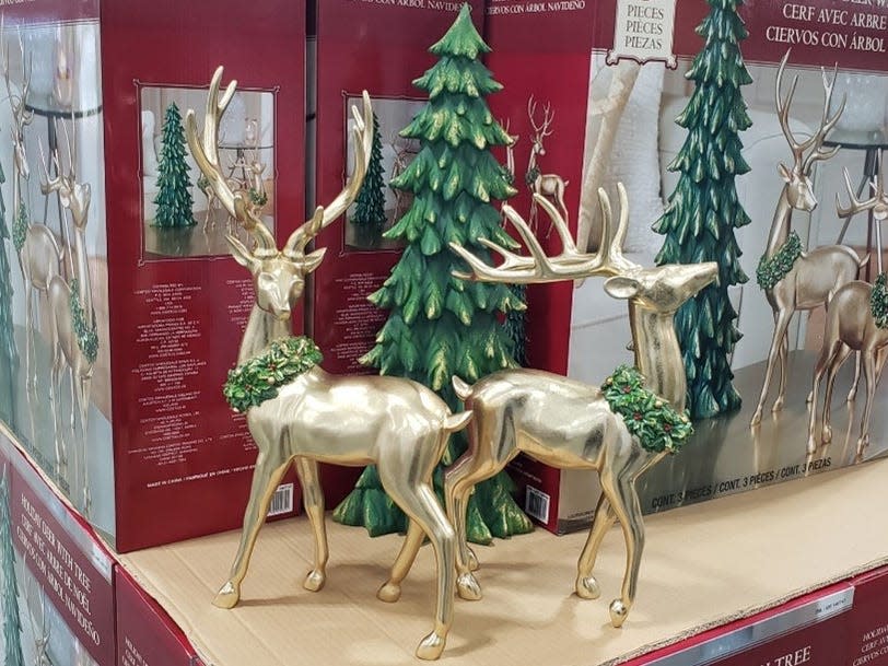 Decorative piece of two deer and an evergreen tree in front of stacked red boxes at Costco