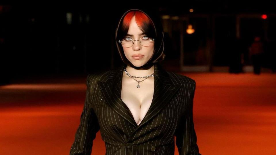 Billie Eilish wears a black pinstripe suit and glasses on the Oscars red carpet 