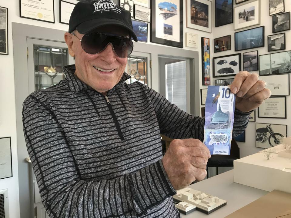 Renowned architect Antoine Predock holds up a Canadian $10 bill while standing in his studio in Albuquerque, N.M., April 30, 2018. The bill features the Canadian Museum for Human Rights in Winnipeg that he designed and was completed in 2014. Predock, whose list of credits includes award-winning buildings around the world, died Saturday, March 2, 2024, at his home in Albuquerque, according to longtime friends and colleagues. He was 87. (AP Photo/Susan Montoya Bryan)