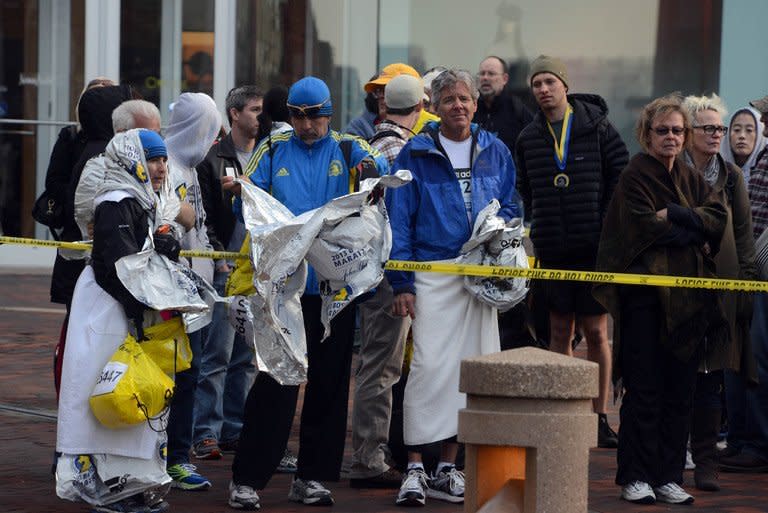 Runners listen to directions from police after two devices detonated at the Boston Marathon on April 15, 2013. The thunderous blasts struck near the finish line of the marathon, long after the winners had crossed. Competitors who were still running when the blasts rocked downtown Boston were diverted elsewhere. Some 27,000 people were entered to take part in the event