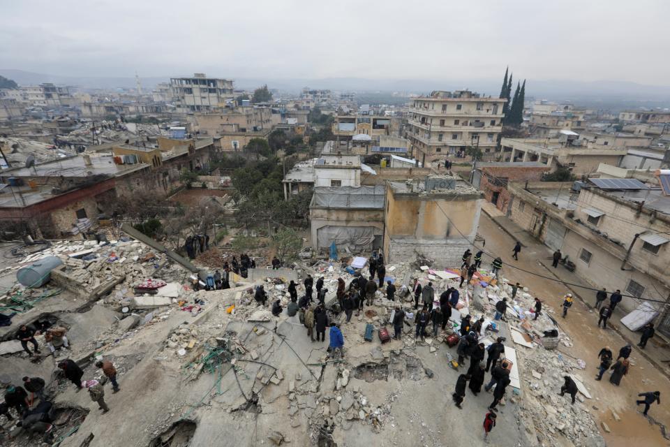 People gather as rescuers search for survivors under the rubble, following an earthquake, in rebel-held town of Jandaris, Syria (REUTERS)