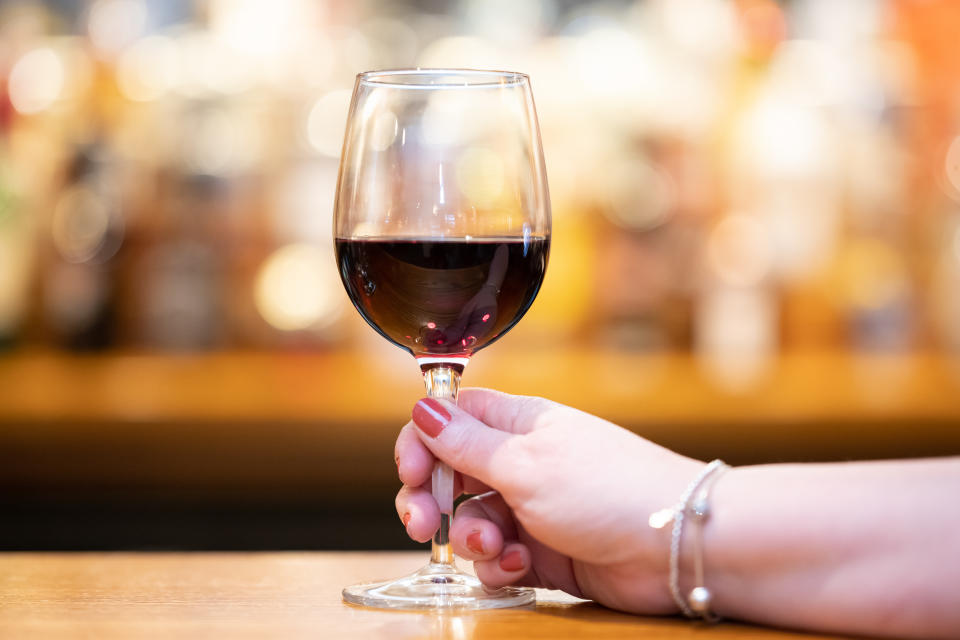 wine alcohol CARDIFF, WALES - FEBRUARY 28: A woman holds a glass of red wine in a pub on February 28, 2020 in Cardiff, Wales. A new law setting a minimum alcohol price will come into force on March 2 under Welsh Government plans. Retailers and bars will have to charge a minimum of 50p per unit, meaning a can of cider could cost at least £1 and a bottle of wine £4.69. A similar system in Scotland has seen alcohol sales fall to the lowest levels since records began. (Photo by Matthew Horwood/Getty Images)