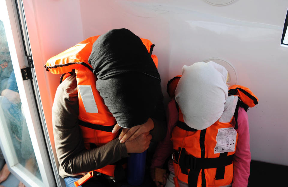 A Syrian woman and her young daughter pray, heads down, that they will reach safety.