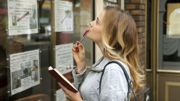 Une femme devant une vitrine immobilière