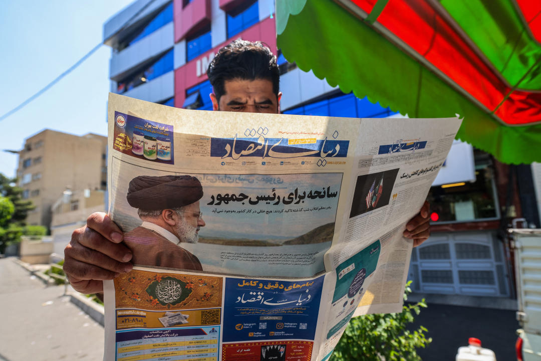 A man reads a newspaper with a front-page report on the crash of the Iranian president's helicopter outside a kiosk in Tehran on May 20, 2024. Iranian President Ebrahim Raisi was declared dead on May 20 after rescue teams found his crashed helicopter in a fog-shrouded western mountain region, sparking mourning in the Islamic republic. (Photo by Atta KENARE / AFP) (Photo by ATTA KENARE/AFP via Getty Images)