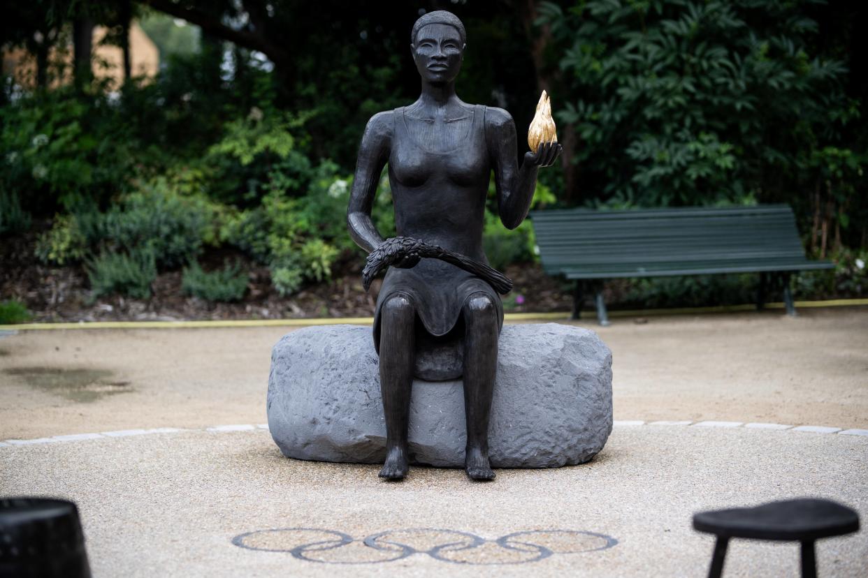 La sculpture d’une femme noire tenant un rameau d’olivier et une flamme dorée dans la création intitulée « Salon » de l’artiste américaine Alison Saar, dans le jardin Charles-Aznavour au pied des Champs-Élysées à Paris, le 21 juin 2024. 