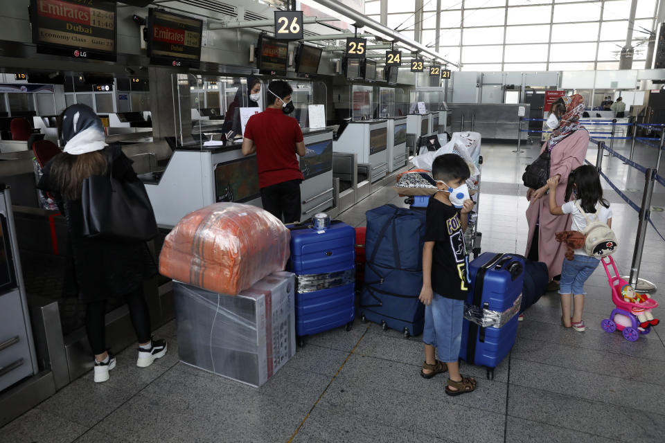 Passengers wearing protective face masks to help prevent the spread of the coronavirus check in at the Emirates airliner counter at Tehran's Imam Khomeini airport, Iran, Friday, July 17, 2020. The first Emirates flight arrived in Iran after nearly 5 months of suspension of the most airliners flights to the country due to the coronavirus outbreak, as Iranian officials at the airport say they are doing everything possible to ensure passengers are not infected, and isolate those with symptoms. (AP Photo/Vahid Salemi)