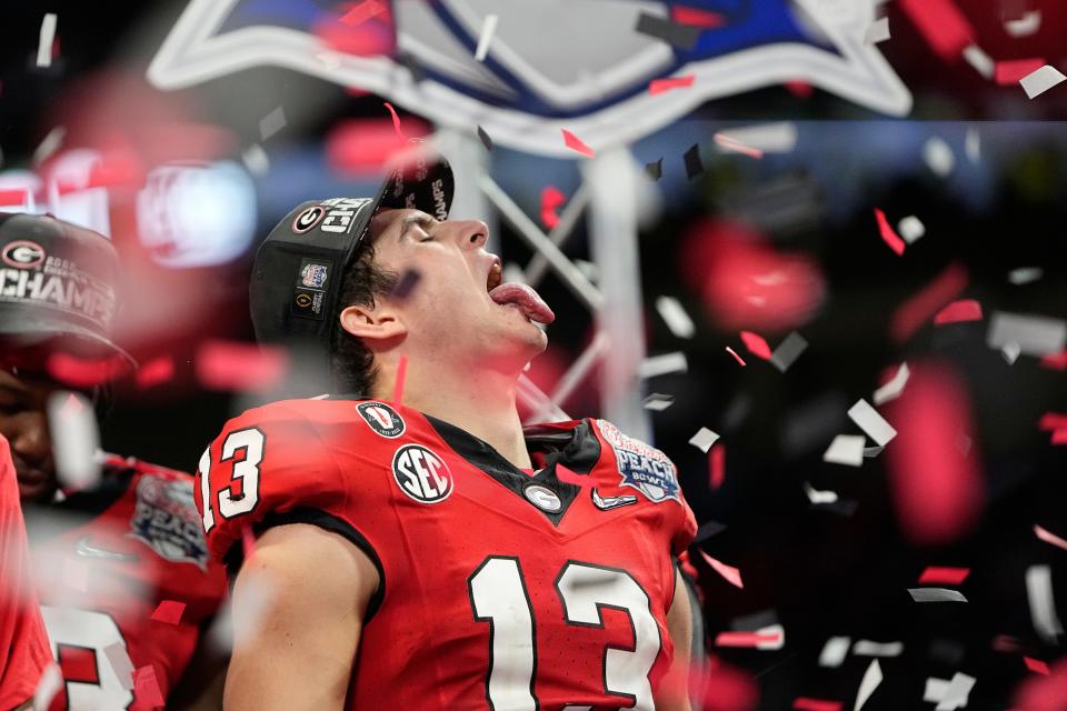 Dec 31, 2022; Atlanta, Georgia, USA; Georgia Bulldogs quarterback Stetson Bennett (13) tries to catch confetti following the Peach Bowl in the College Football Playoff semifinal against the Ohio State Buckeyes at Mercedes-Benz Stadium. Georgia beat Ohio State 42-41. Mandatory Credit: Adam Cairns-The Columbus Dispatch