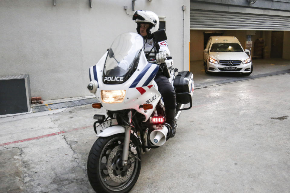 A police motorcycle escorts a hearse, right, carrying the body of former Zimbabwe President Robert Mugabe leaving the Singapore Casket Funeral Parlour for the airport in Singapore Wednesday, Sept. 11, 2019. Mugabe died Friday, Sept. 6 at a hospital in Singapore at age 95. (AP Photo/Danial Hakim)