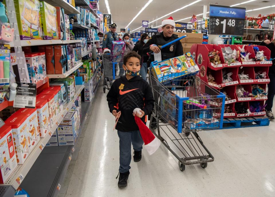Cameron Johnson, 7, of Fountainville, races down an aisle as Dublin Borough Police Ofc. Ismael Ramos follows with a cart full of toys during Plumstead Township Police Department's 5th annual Shop with a Cop event at Walmart in Hilltown Township on Tuesday, December 8, 2021. Funded by community donations, the program paired law enforcement officers from 11 local departments with more than 100 kids to help them shop for presents for themselves and their families.