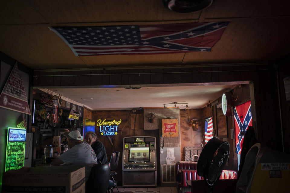 People sit in a bar decorated with an American flag and confederate flags before noon in Meridian, Miss., Wednesday, Oct. 7, 2020. Today, voters in Mississippi face a series of government-created barriers that make it, according to a study in the Election Law Journal in 2018, far and away the most difficult state in which to vote. (AP Photo/Wong Maye-E)