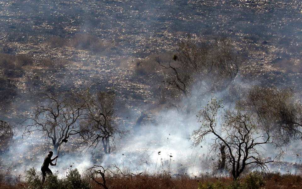 A Palestinian tries to extinguish a fire in an olive grove near the Palestinian village of Burin in the northern West Bank by the Israeli settlement of Yitzhar, on Oct. 16, 2019. | Jaafar Ashtiyeh—AFP via Getty Images