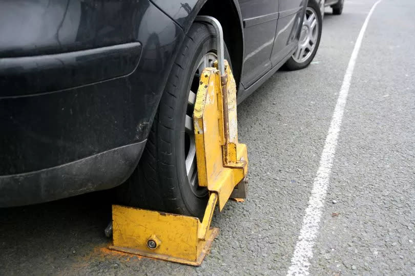 A car parked in a parking bay with a clamped wheel