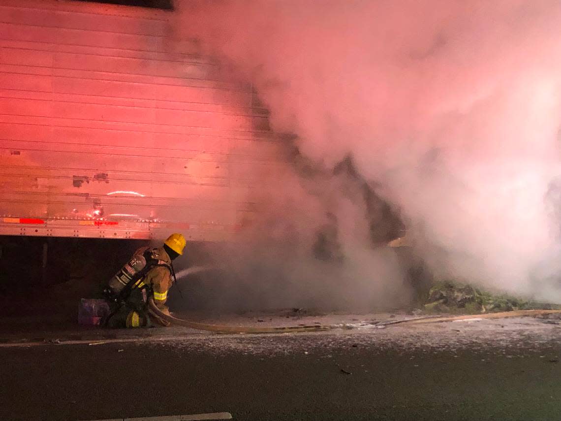 A firefighter sprays water on a semi-truck trailer filled with asparagus that caught fire on Highway 46 East in Paso Robles around 4 a.m. on July 25, 2022.