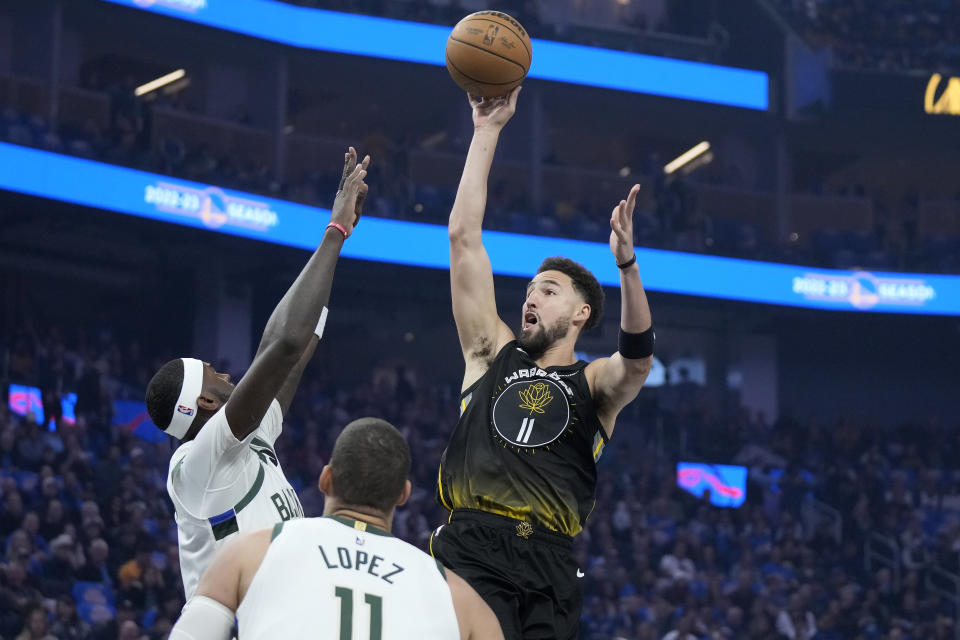 Golden State Warriors guard Klay Thompson, right, shoots against Milwaukee Bucks forward Bobby Portis Jr., left, and center Brook Lopez during the first half of an NBA basketball game in San Francisco, Saturday, March 11, 2023. (AP Photo/Jeff Chiu)