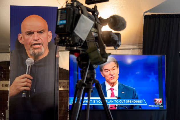 Republican Mehmet Oz, right, is seen live on a monitor in the media tent, next to a poster of Democrat John Fetterman as the two US Senate candidates hold their first and only debate. (Photo: via Associated Press)