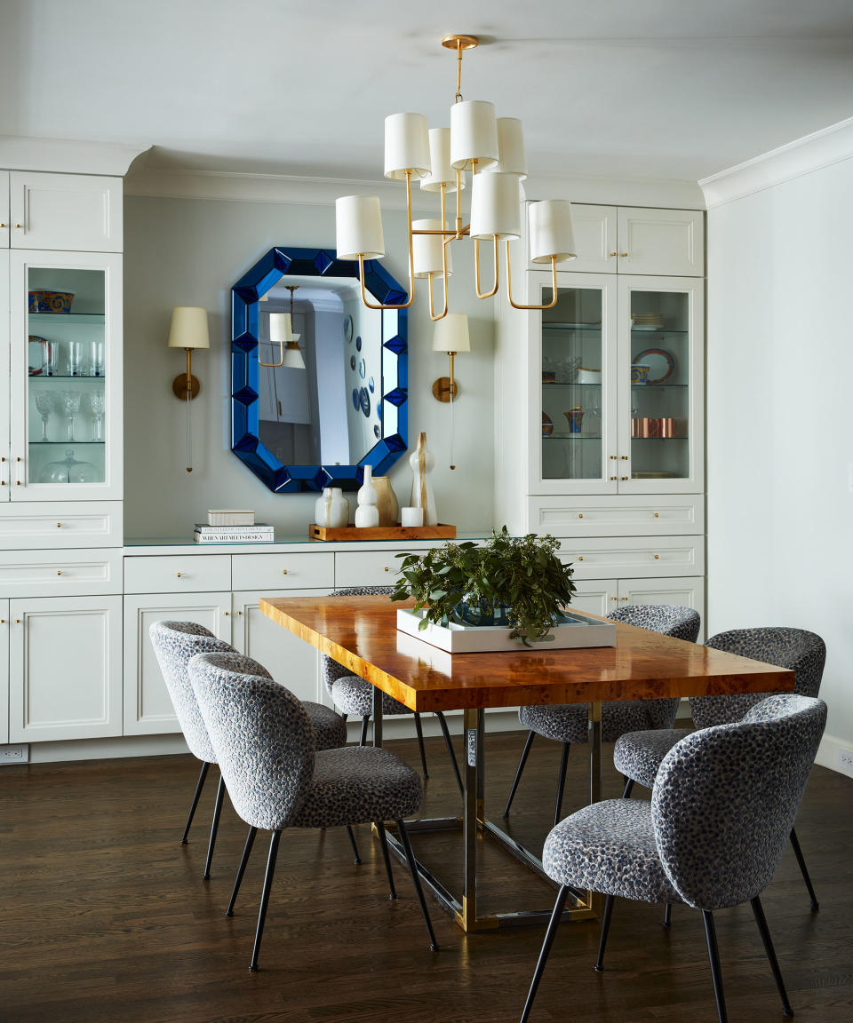 Jewel thick trim angular mirror at the head of a dining room table reflecting artistic pendant  lighting