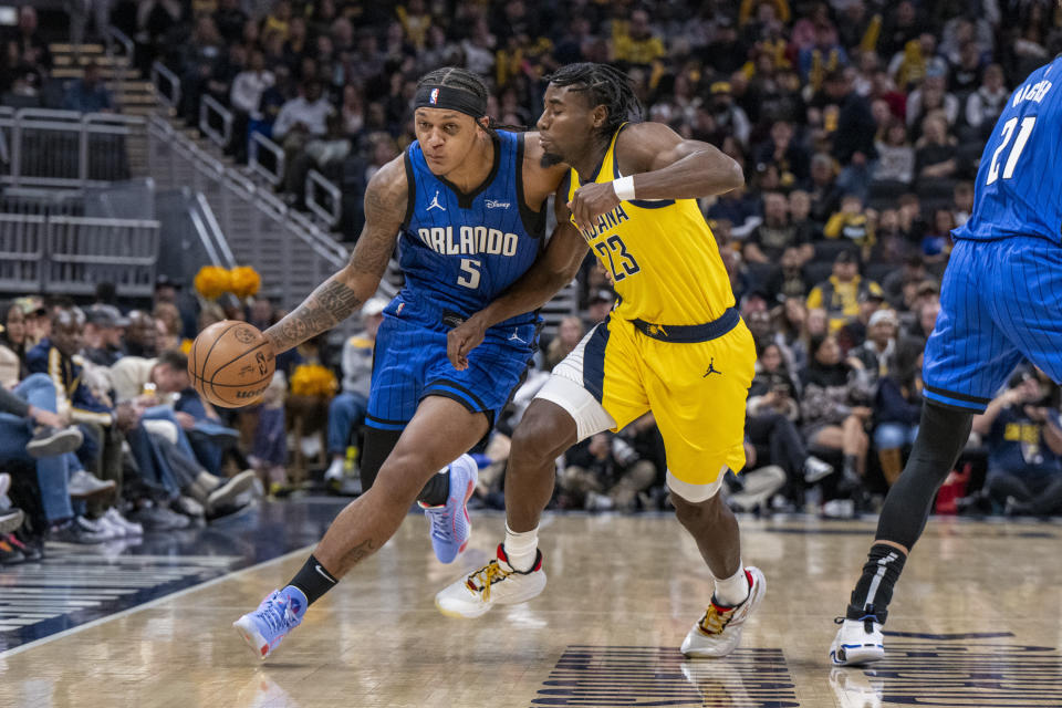 Orlando Magic forward Paolo Banchero (5) drives the ball against the defense of Indiana Pacers forward Aaron Nesmith (23) during the first half of an NBA basketball game in Indianapolis, Sunday, Nov. 19, 2023. (AP Photo/Doug McSchooler)