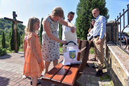 A local resident casts her vote into a mobile ballot box during a parliamentary election in the village of Maidan in Lviv Region