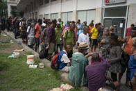 Homeless gather for a free cup of coffee and bread, distributed by Eli Ferreira, wearing hat, who started serving free breakfast to the hungry daily since the outbreak of the new coronavirus, in downtown in Rio de Janeiro, Brazil, Monday, March 30, 2020. Ferreira, who used to serve food twice a week before the outbreak, said he knows he is breaking the rules of social distancing but that "what counts now is the human side." (AP Photo/Leo Correa)