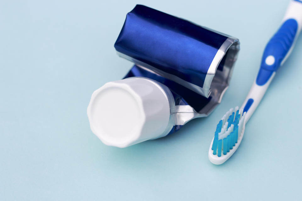 Empty tube of toothpaste and toothbrush on blue background