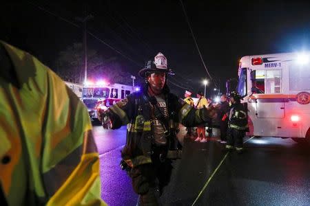 A firefighter clears the area while emergency responders attend to a train that sits derailed near the community of New Hyde Park on Long Island in New York, U.S, October 8, 2016. REUTERS/Eduardo Munoz