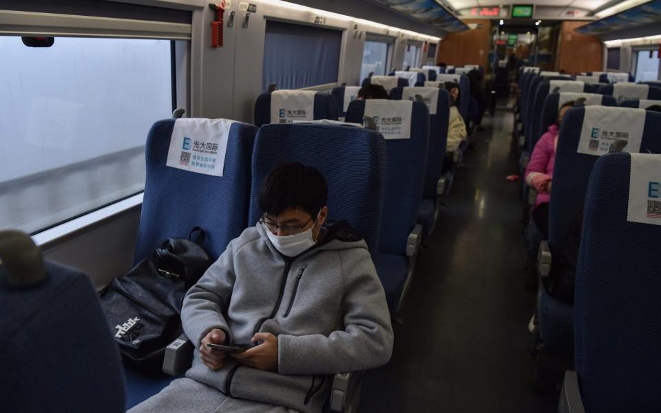 A young man wearing a protective facemask sits on a train usually full with passengers ahead of the Lunar New Year as he travels from the Chinese city of Shanghai to his hometown of Wuhan - AFP