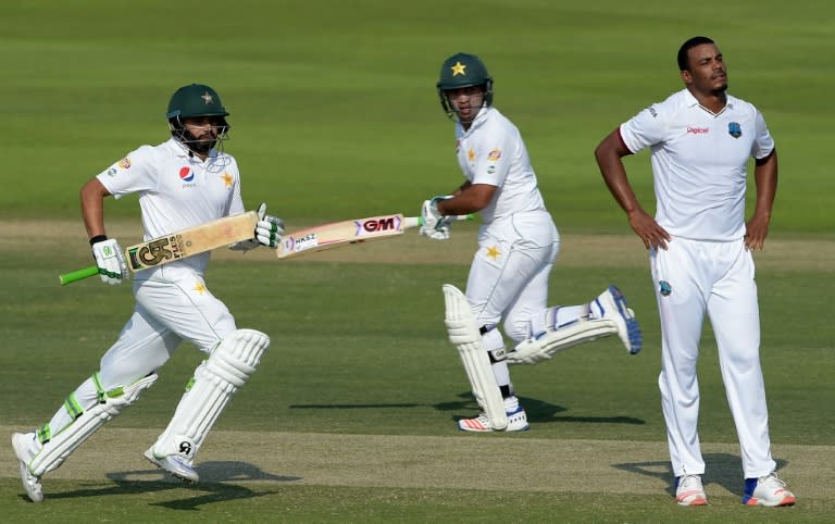 Pakistan batsmen Azhar Ali (L) and Sami Aslam (C) run between the wicket as West Indies' bowler Shannon Gabriel looks on during the third day of the second Test in Abu Dhabi on October 23, 2016