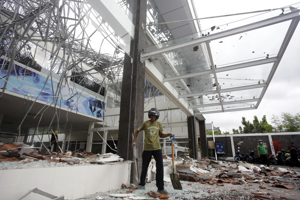 A man cleans up at a building damaged by an earthquake in Bali, Indonesia, Monday, Aug. 6, 2018. A powerful earthquake struck the Indonesian tourist island of Lombok on Sunday, shaking neighboring Bali, one week after another quake on Lombok killed more than a dozen. (AP Photo/Firdia Lisnawati)