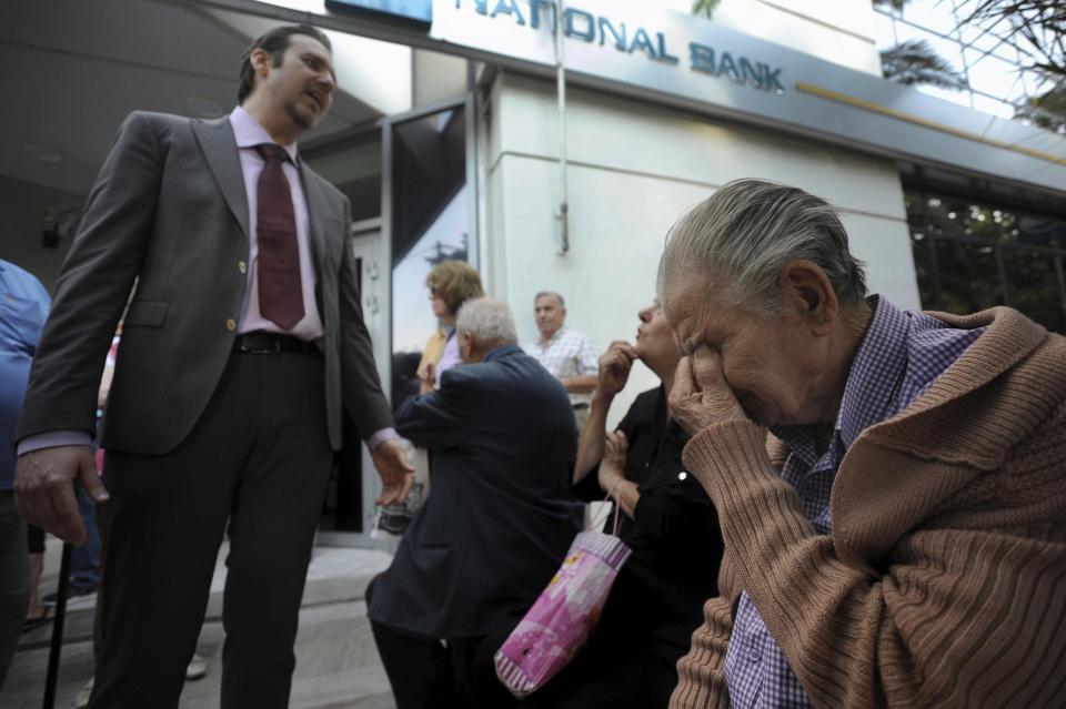 Un gerente de una sucursal bancaria explica la situación a los jubilados que esperan en la puerta.