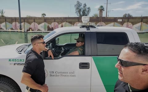 Border Patrol agents gather along the border fence in Calexico, California - Credit: SANDY HUFFAKER/AFP/Getty Images