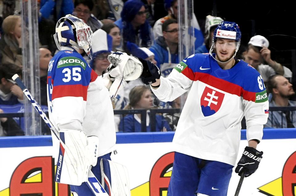 Goalkeeper Adam Huska and Pavol Regenda of Slovakia celebrate their second goal during the 2022 IIHF Ice Hockey World Championships semi-final match between Finland and Slovakia in Tampere, Finland, Thursday, May 26, 2022. (Vesa Moilanen/Lehtikuva via AP)