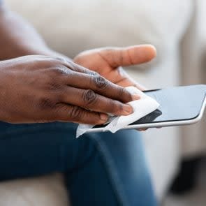 Unrecognizable Man Disinfecting and cleaning Smartphone Screen With a Wipe