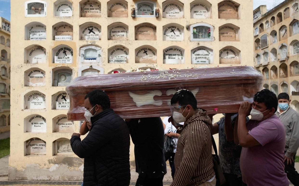 Relatives of a Covid-19 victim carry a coffin at the General Cemetery in the central city of Huanuco - OSCAR ROSARIO /AFP