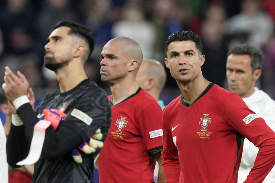 Portugal's goalkeeper Diogo Costa, Pepe and Cristiano Ronaldo, from left, react after losing a quarterfinal match between Portugal and France at the Euro 2024 soccer tournament in Hamburg, Germany, Friday, July 5, 2024. France won a penalty shoot out 4-3 after the match ended in a 0-0 draw. (AP Photo/Martin Meissner)