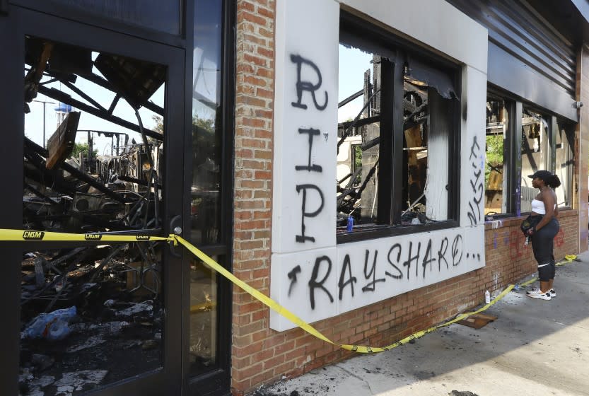 FILE - In this June 15, 2020 file photo, a woman looks at the interior of the burned Wendy's restaurant in Atlanta. Investigators said Saturday, June 20, they have issued an arrest warrant for a woman in the burning of a Wendy's restaurant in Atlanta during protests over the police shooting of Rayshard Brooks. (Curtis Compton/Atlanta Journal-Constitution via AP)