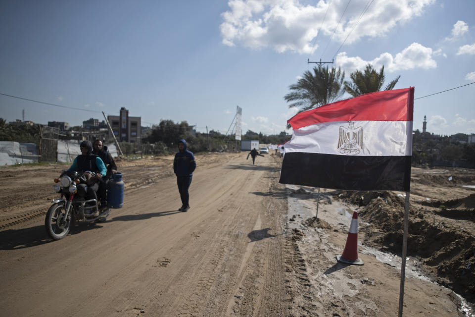 Palestinians pass an Egyptian flag on the side of a street in Beit Lahiya, northern Gaza Strip, Jan. 25, 2022. After years of working behind the scenes as a mediator, Egypt is taking on a much larger and more public role in Gaza. In the months since it brokered a Gaza cease-fire last May, Egypt has sent crews to clear rubbled and promised to build vast new apartment complexes, and billboards of its president Abdel-Fattah el-Sissi, are a common sight. (AP Photo/Khalil Hamra)