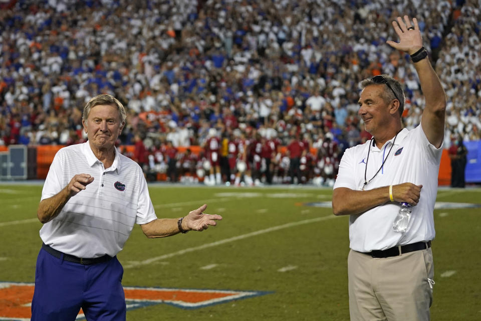 Former Florida head coaches Steve Spurrier, left, and Urban Meyer are recognized during a timeout in the first half of an NCAA college football game between Florida and Florida Atlantic, Saturday, Sept. 4, 2021, in Gainesville, Fla. Meyer is coach of the NFL's Jacksonville Jaguars. (AP Photo/John Raoux)