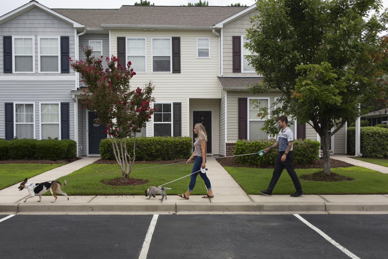 Gabrielle Smychynsky, left, a first time home buyer, and her fiancé Wes White, right, take their dog Lucy and their seven-week-old puppy Ada for a walk in their neighborhood in Myrtle Beach, South Carolina on July 13, 2022. (Credit: Madeline Gray for The Washington Post via Getty Images)