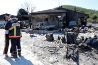 <p>A woman hugs a fireman near charred debris of vehicles that were destroyed by fire in a parking lot for camping cars in Bormes-les-Mimosas, in the Var department, France, July 26, 2017, after firefighters evacuated thousands of campers and local residents when a wildfire broke out on France’s tourist-thronged Riviera coast overnight. (Jean-Paul Pelissier/Reuters) </p>