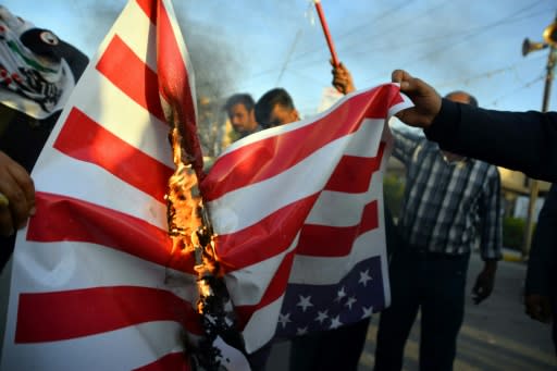 Iraqis torch an American flag after US air strikes against a pro-Iran group kill at least 25 fighters