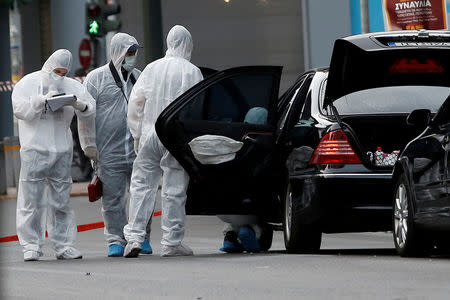 FILE PHOTO: Forensic officers inspect the car of former Greek Prime Minister and former central bank chief Lucas Papademos following the detonation of an envelope injuring him and his driver, in Athens, Greece, May 25, 2017. REUTERS/Costas Baltas/File Photo