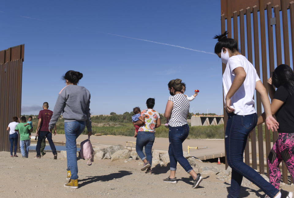 FILE - A group of Brazilian migrants make their way around a gap in the U.S.-Mexico border in Yuma, Ariz., seeking asylum in the United States after crossing over from Mexico, June 8, 2021. border. The Biden administration has unveiled new procedures to handle asylum claims at the U.S. southern border, hoping to decide cases in months instead of years. The rules empower asylum officers to grant or deny claims, an authority that has been limited to immigration judges for people arriving at the border with Mexico. (AP Photo/Eugene Garcia, File)