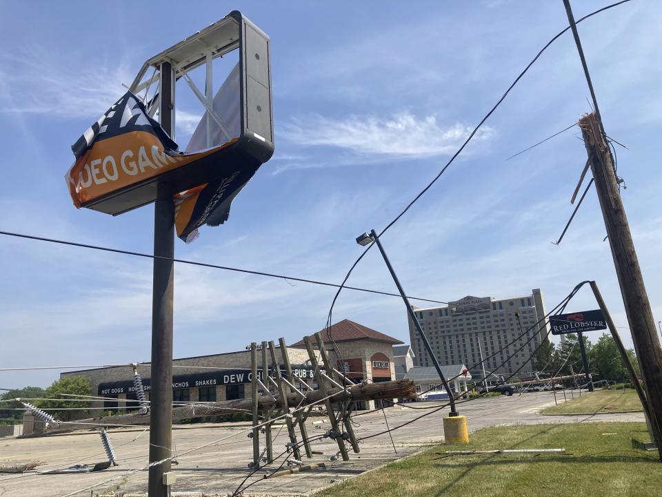 Near a damaged sign, a utility pole lies in a parking lot on Friday, June 30, 2023, snapped off in derecho winds that hit Springfield, Ill., a day earlier along with a string of others on an east-side commercial strip just west of Interstate 55. (AP Photo/John O'Connor)