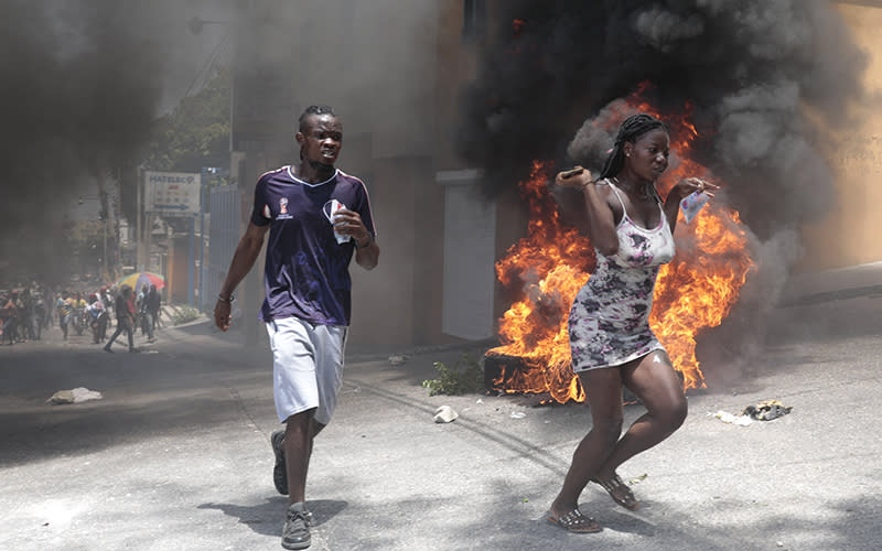 Demonstrators run past tires set on fire during a protest